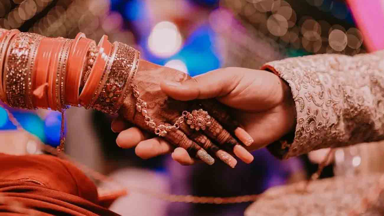 The bride and groom are holding each other's hands on the occasion of the wedding.