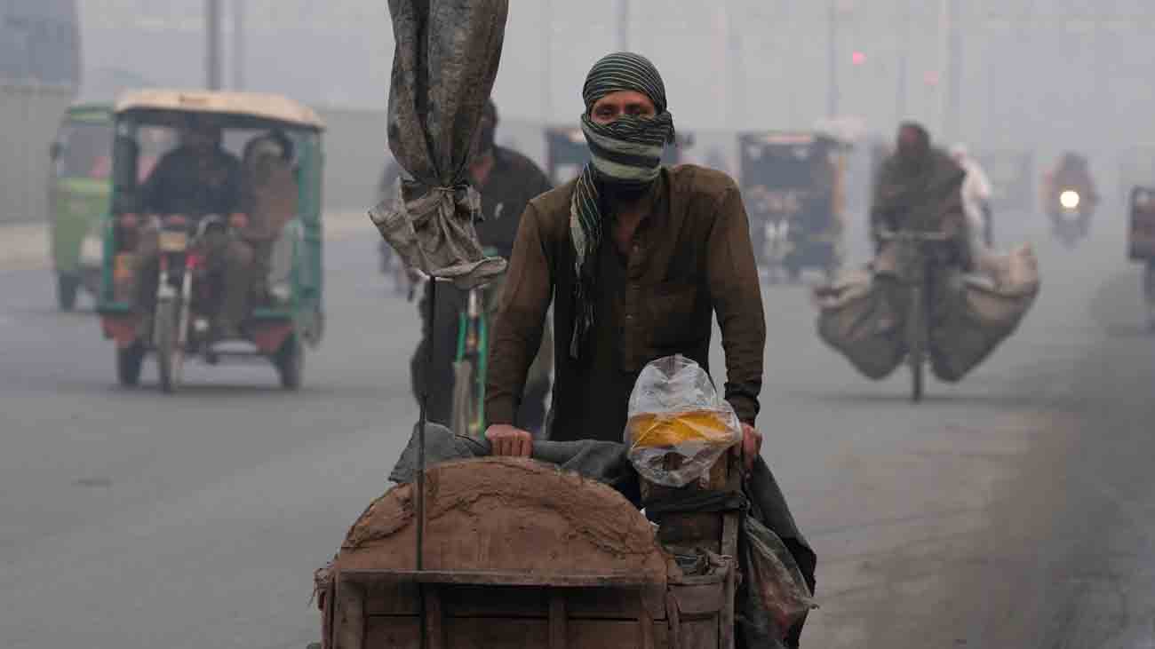 A trucker is walking on the road wearing a cloth over his face to avoid the polluted air.