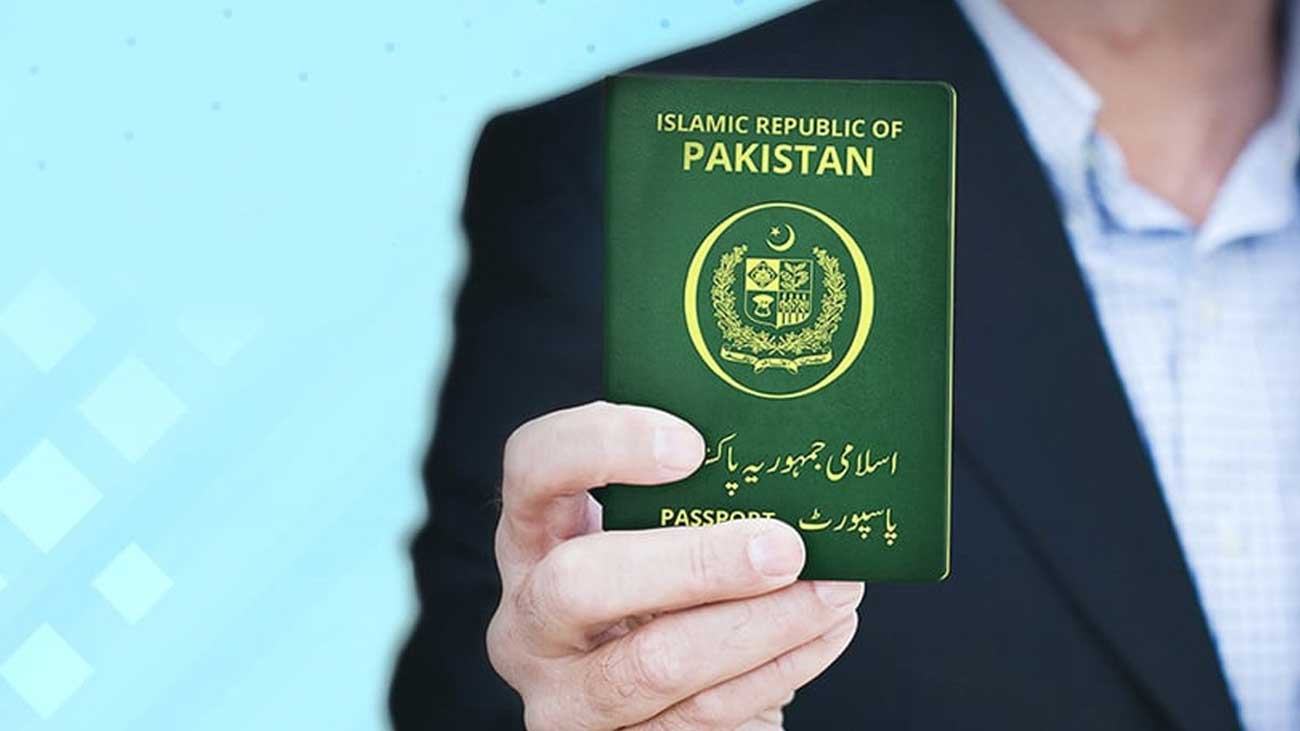 ایک شخص اپنے ہاتھ میں پاکستانی پاسپورٹ لیے کھڑا ہے