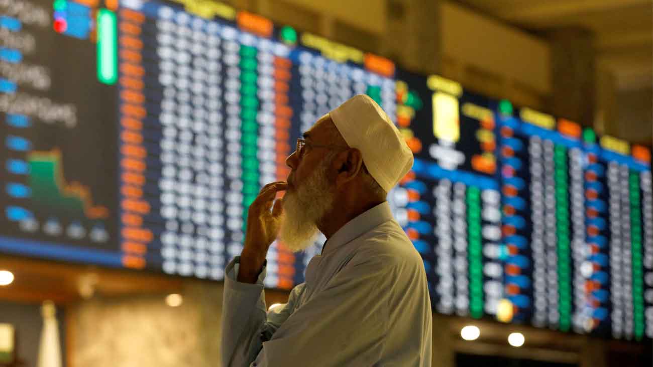 A stock broker reacts while monitoring the market on the electronic board displaying share prices during trading session at the Pakistan Stock Exchange